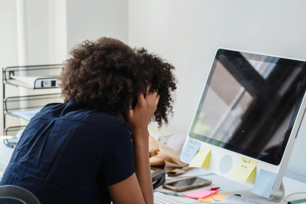 Frustrated project manager with head in hands at a cluttered desk, struggling to manage projects and tasks without the right tools.