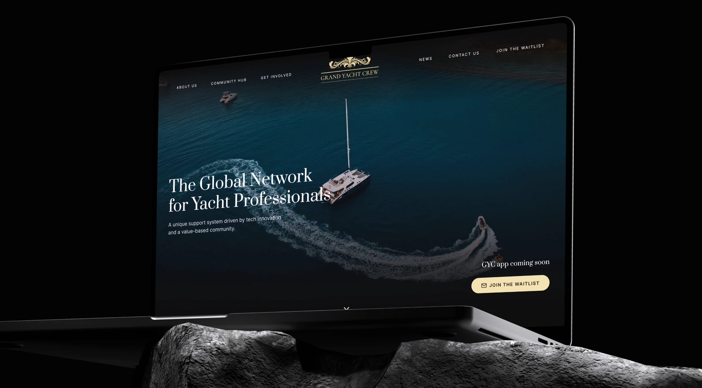 Laptop screen showing Grand Yacht Crew website with yacht and boat on blue water in background.