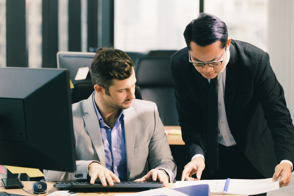  Two professionals in formal attire examining information on a screen.