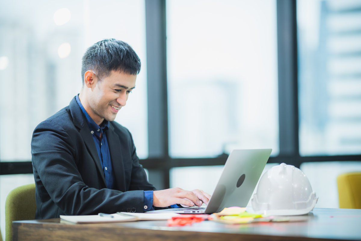 An Asian businessman focused on his laptop in a professional office setting. Illustrates the benefits of AWS Managed Services.