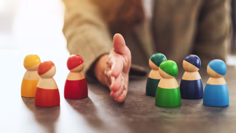 person and wooden figures represents unity and the vital roles we play in 2025.