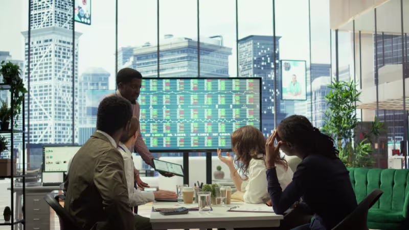 Business professionals in an office collaborating while viewing a screen displaying insights on offshore loyalty strategies