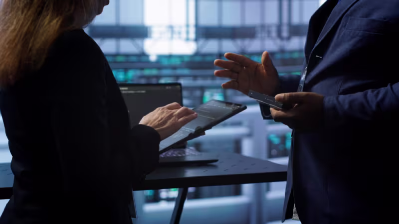 Two colleagues engaged in a conversation over a tablet, emphasizing the importance of a NetSuite technical consultant.