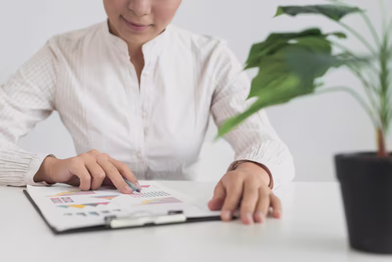 A woman wearing a white shirt studies a chart related to the 2026 NetSuite Administrator Cost Guide comparison.