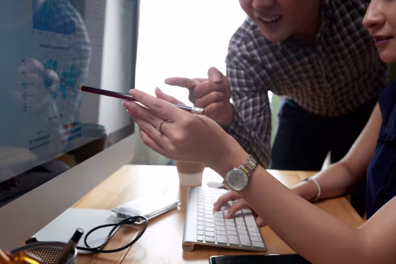 A man and woman review a computer screen together, working on a trial project for a developer.