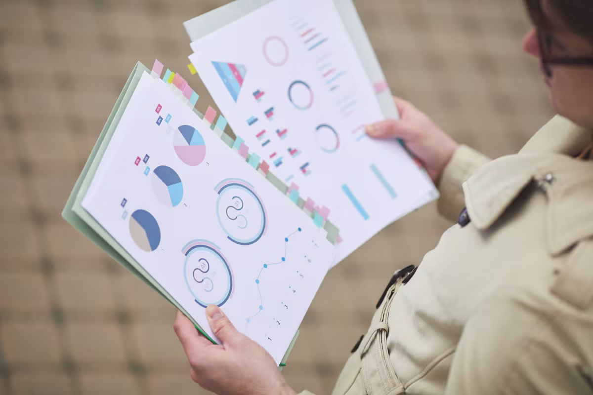 A person holds a folder displaying graphs and diagrams related to cost reduction in accounting process outsourcing for ERP.