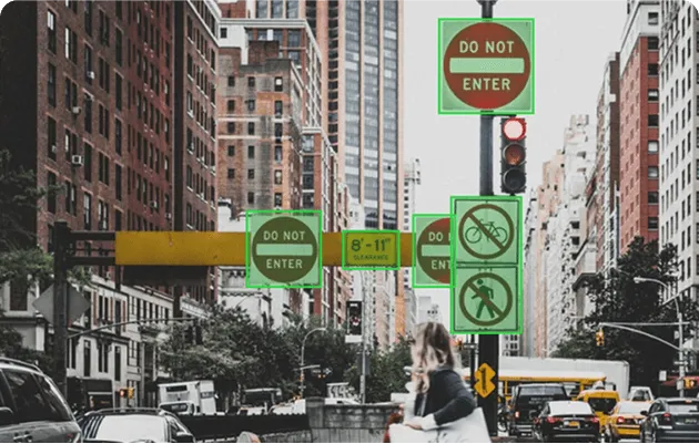 Urban street scene with multiple 'Do Not Enter' signs, no bicycles allowed, and no pedestrian crossing signs on a city street with traffic and tall buildings.