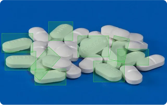 Pile of white and light green oblong tablets scattered on a blue surface.