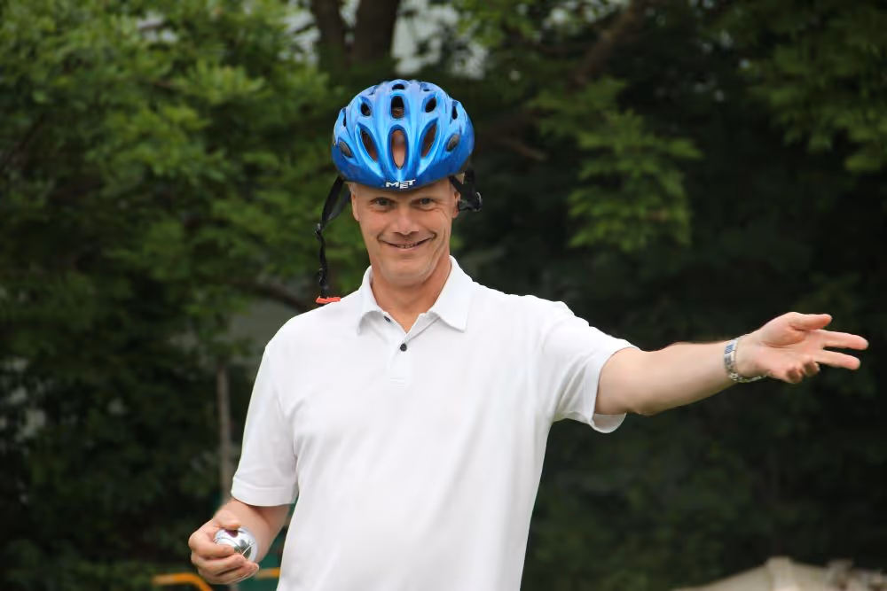 Anders ler och har på cykelhjäm. I bagrunden syns träd.