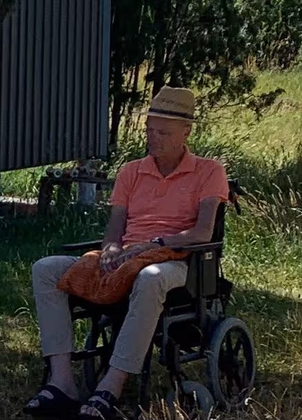 Anders sitter i sin rullstol i trädgården.