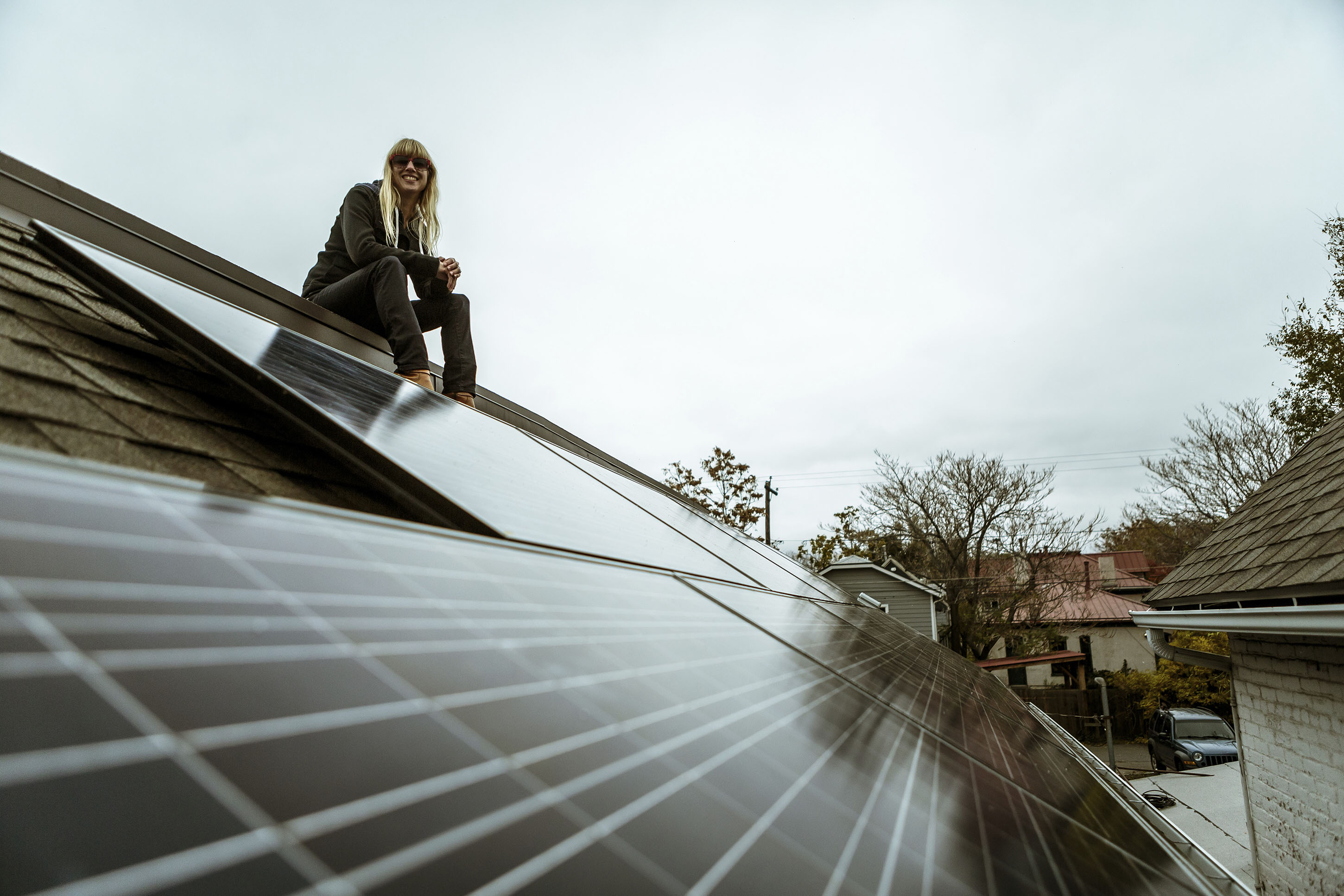 Woman sitting on a roof smiling with a solar system installed