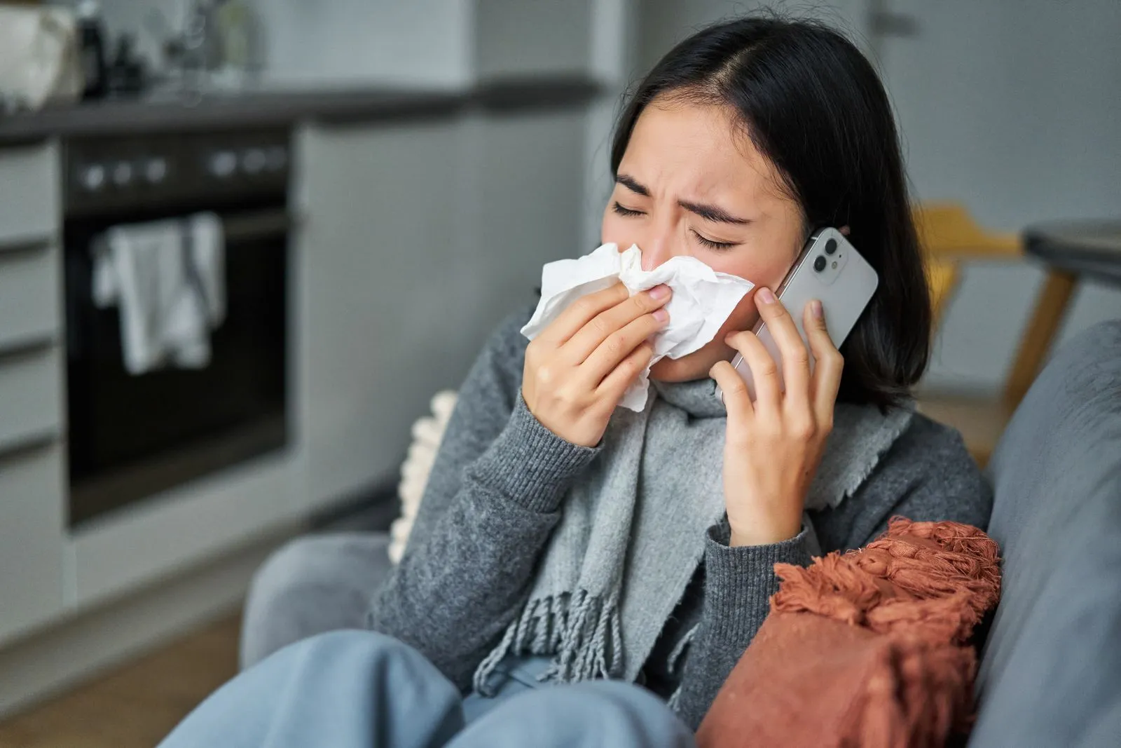 young woman sneezing and holding a napkin while staying at home