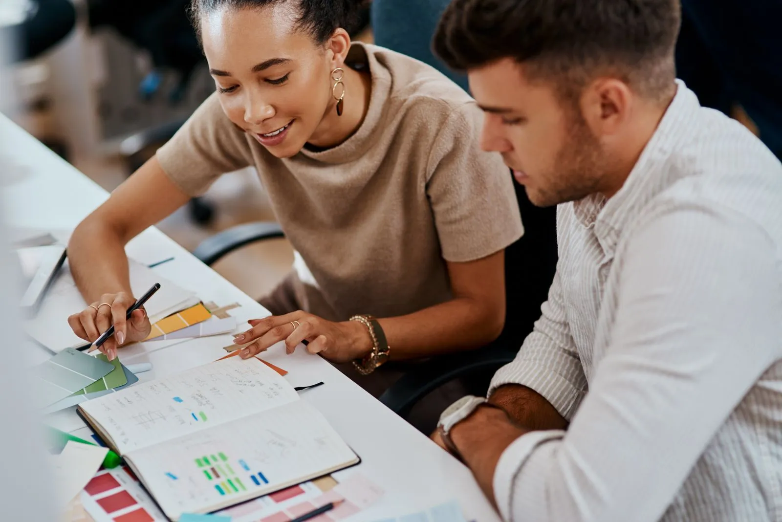 Two employees, a woman and man, working together at the task in the modern office