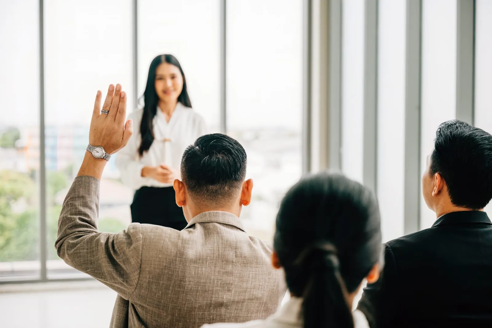 Employees raising hands during a training session or meeting, showing active participation and engagement