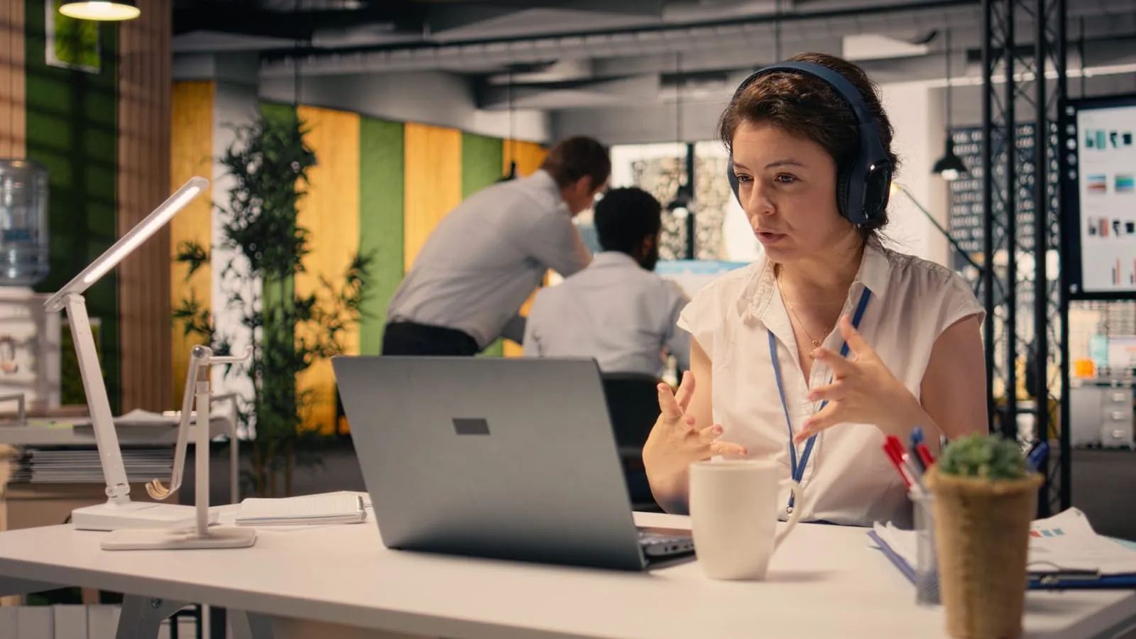 A professional woman in the modern office working in headphones