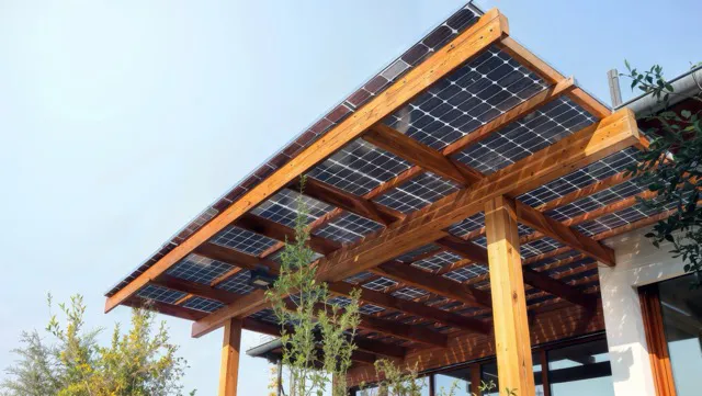 Pérgola de madera con paneles solares instalados en el techo bajo un cielo despejado.