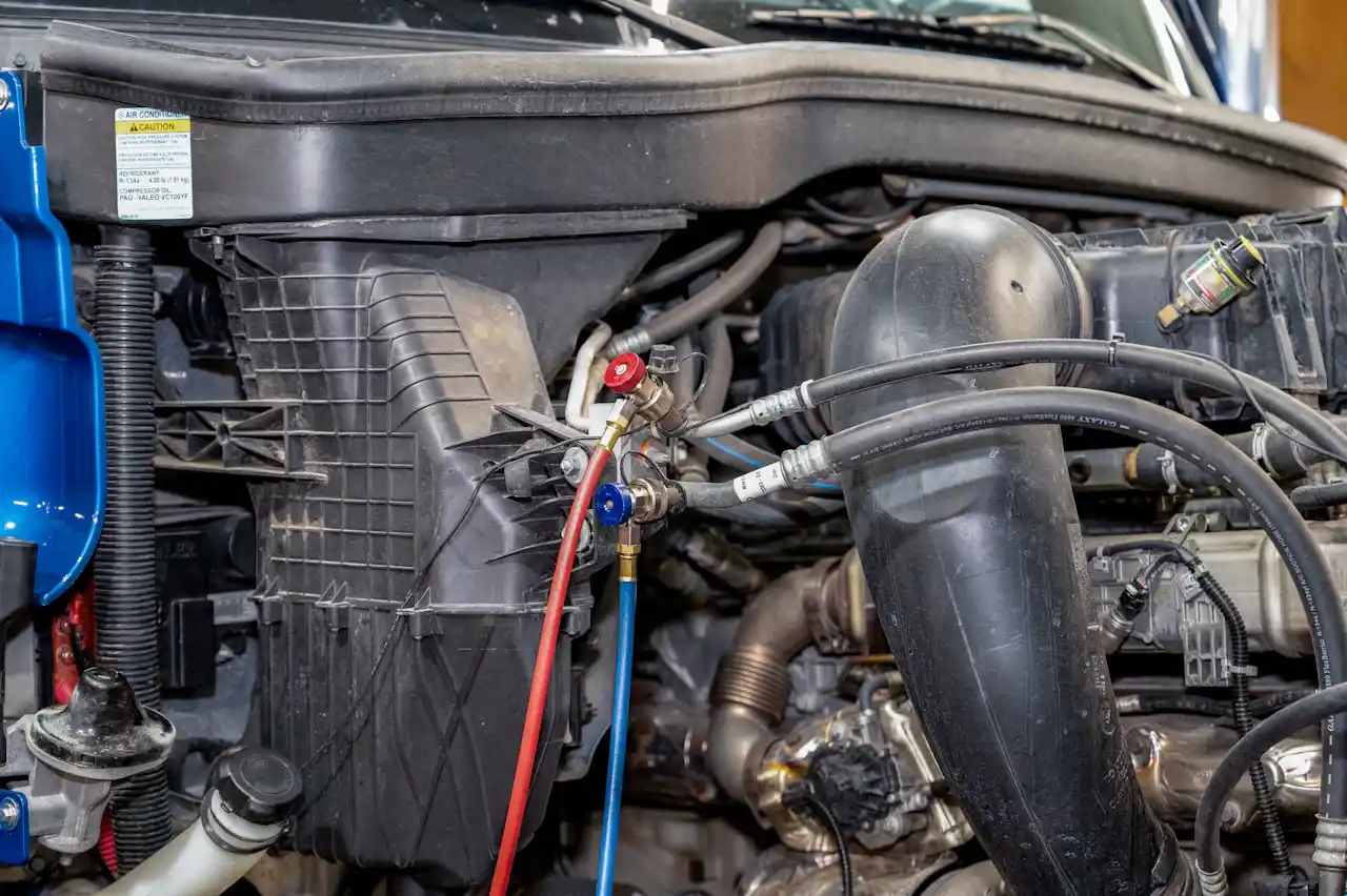A/C service with manifold gauges connected to a heavy-duty truck engine for air conditioning diagnostics.