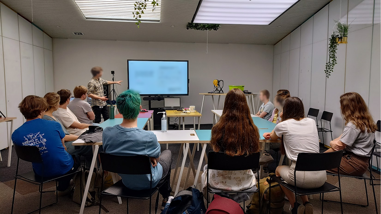Picture of a focus group with a central screen surrounded by a group of participants and one presenter/
