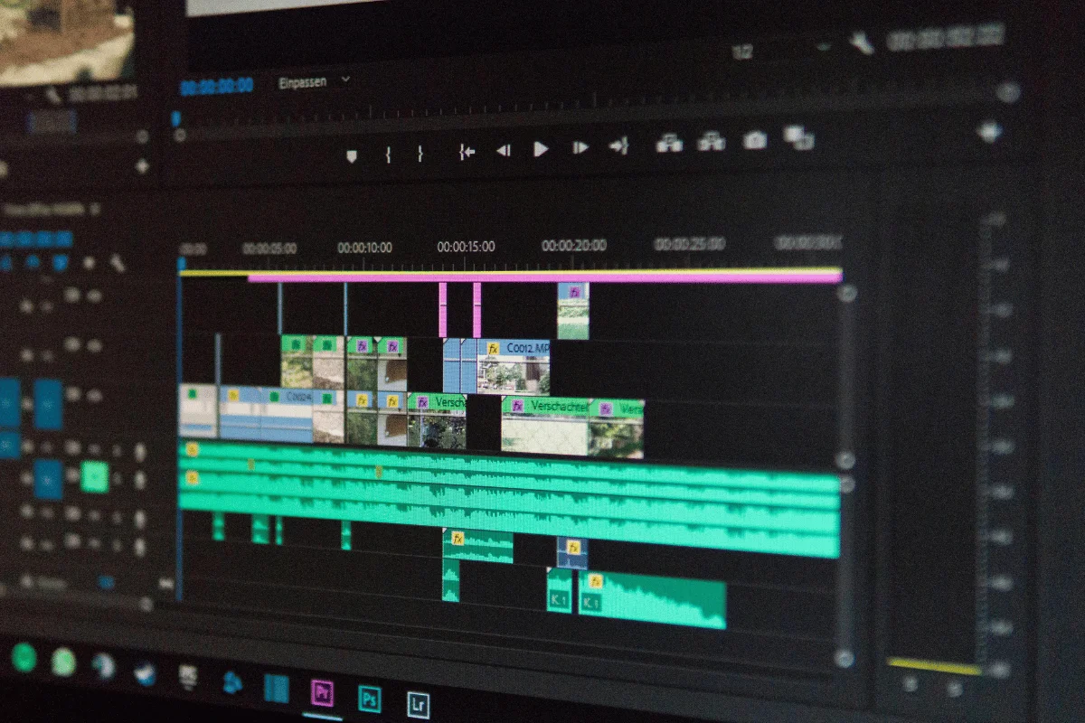 Close-up of a video editing timeline in Adobe Premiere Pro, featuring audio and video tracks with colorful clips and soundwaves.
