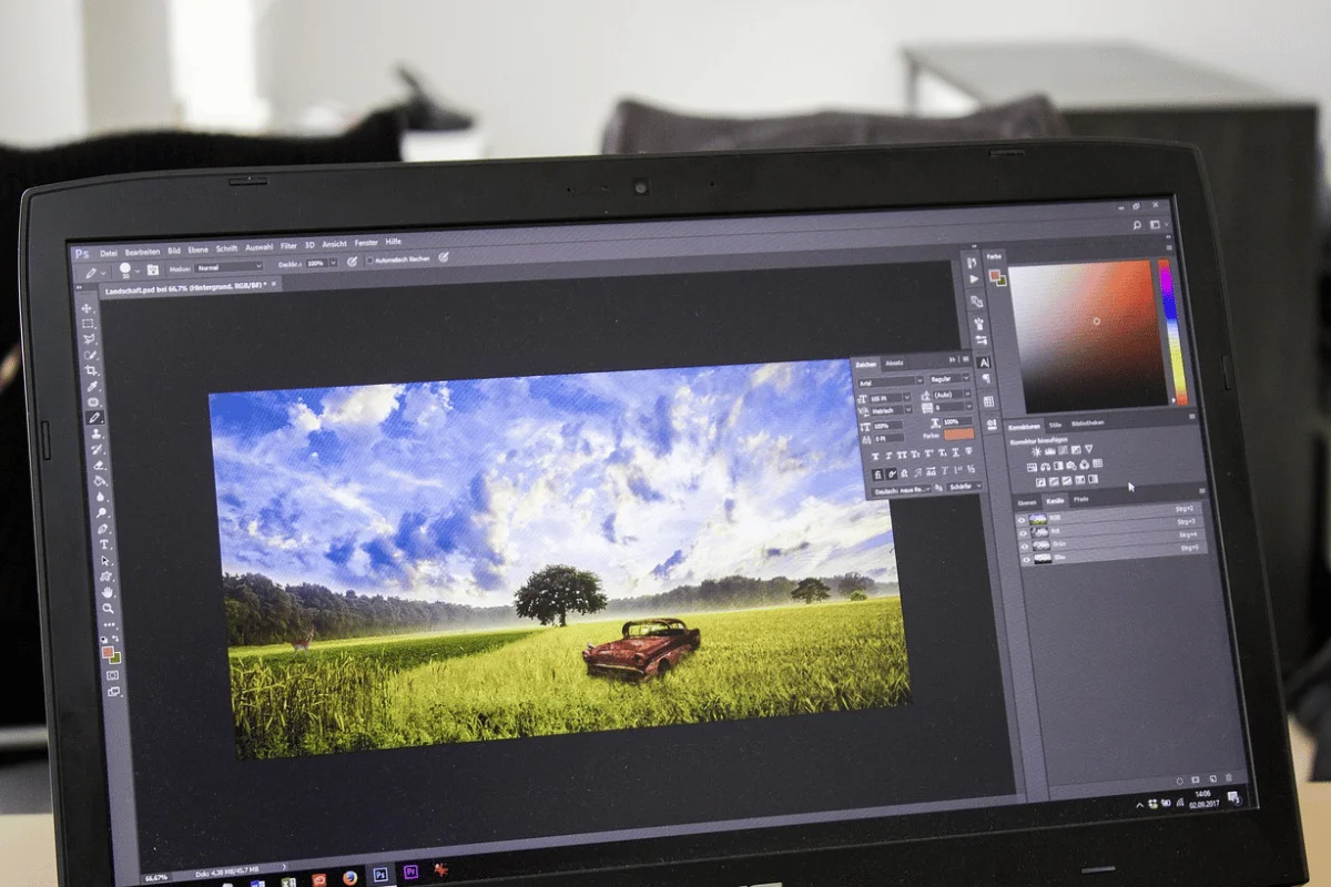 A laptop screen displays a photo editing program with an image of a rusty car in a lush green field under a vibrant blue sky, conveying a serene rural scene.