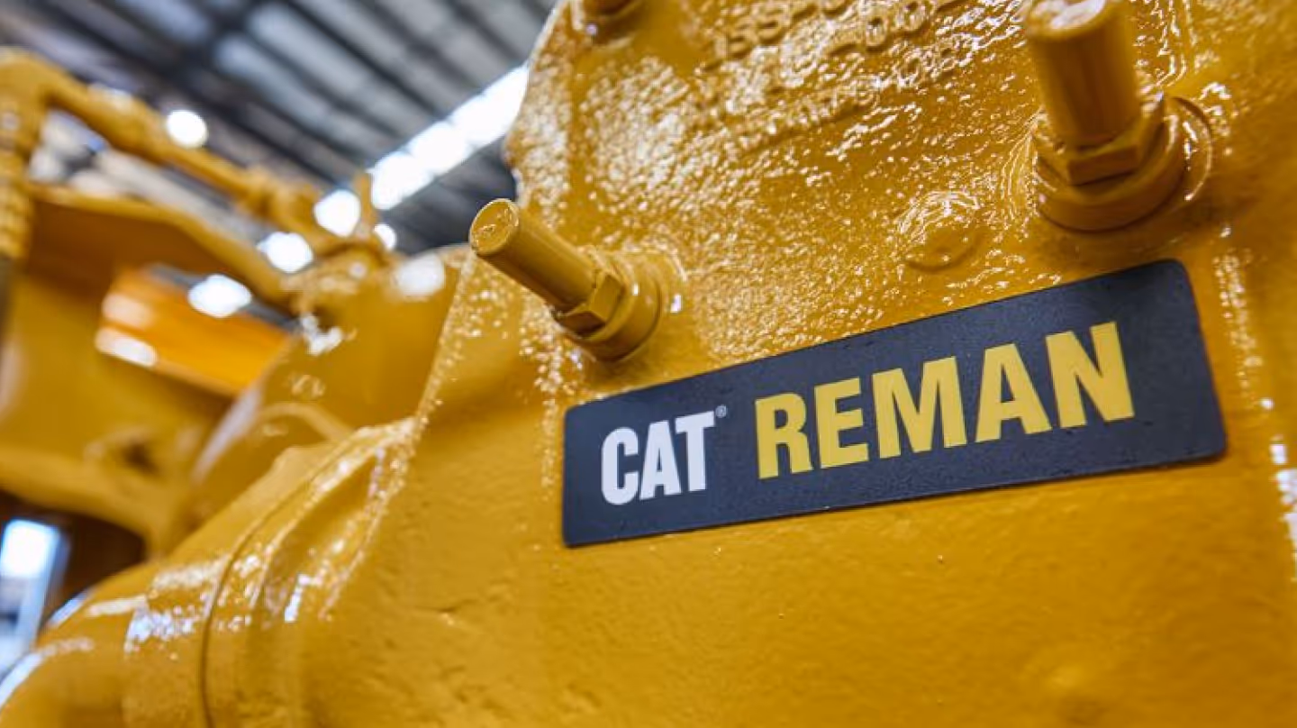 Close-up of a yellow Caterpillar machine part with the CAT Reman logo, symbolizing the brand’s remanufacturing program.