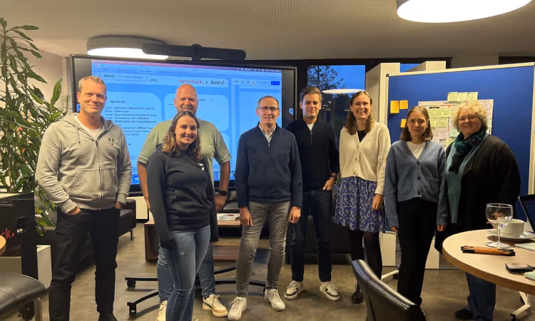 Group photo of the project team from Kettelhack and koorvi during a workshop for the “Closing the Loop” project. In the background, a screen shows a Miro session on the digital implementation of take-back systems.