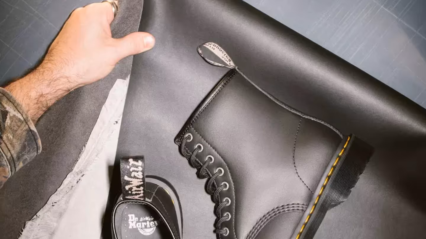Nahaufnahme einer Hand, die Leder neben einem schwarzen Dr. Martens Boot hält.