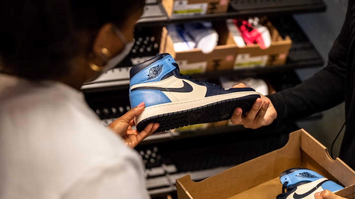 Photo of a customer inspecting a refurbished Nike sneaker in a store environment.