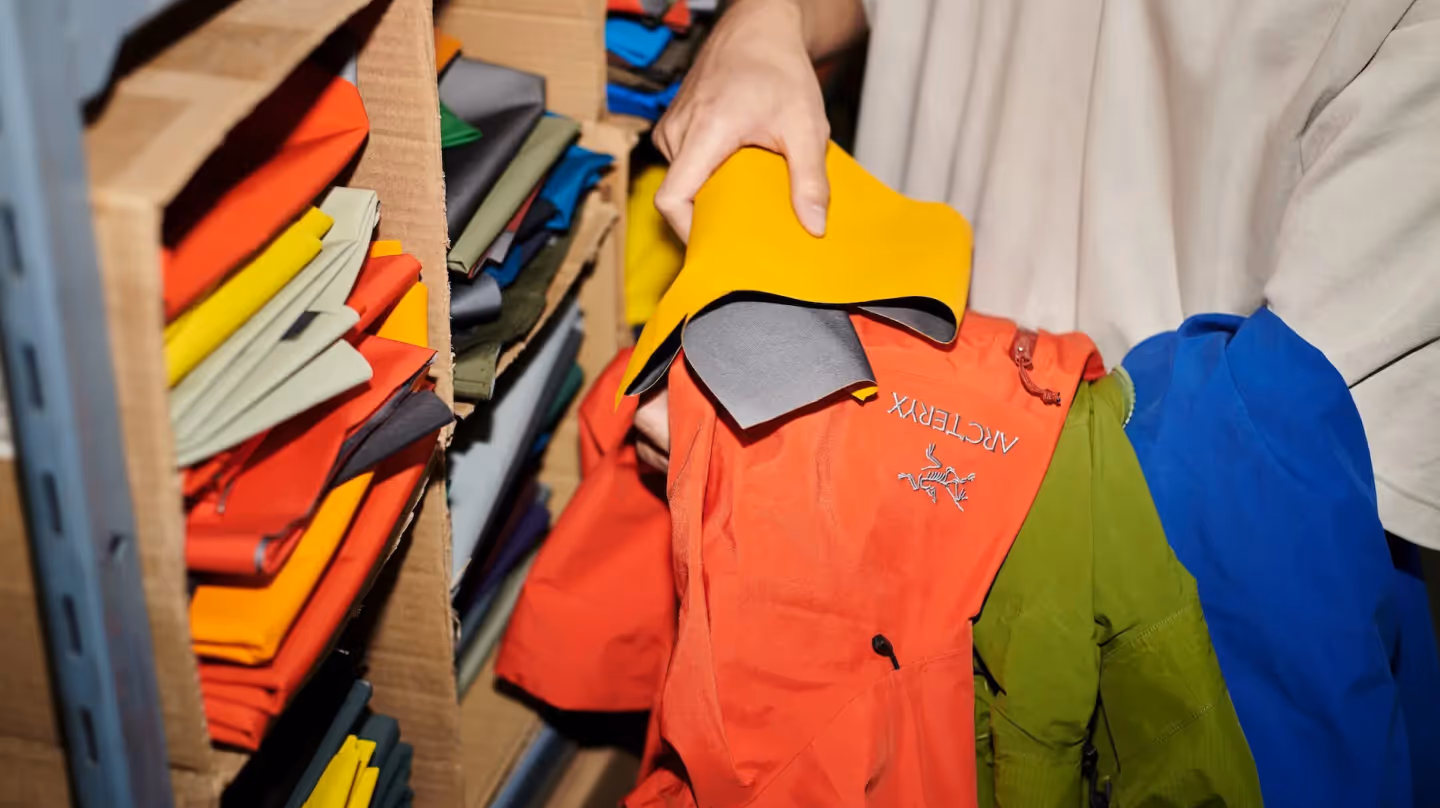 Person selecting colorful fabric patches to repair or upcycle Arc’teryx jackets