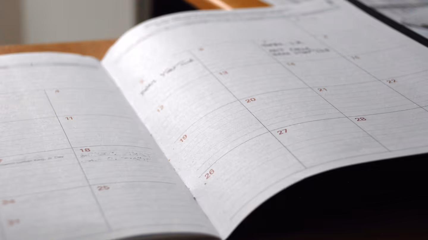 Open calendar with a monthly overview, lying on a desk.
