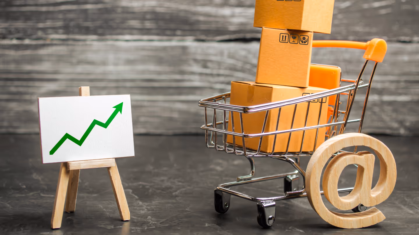 Symbolbild eines Einkaufswagens mit Kartons neben einem grünen Aufwärtspfeil – steht für umsatzsteigernden Wiederverkauf.