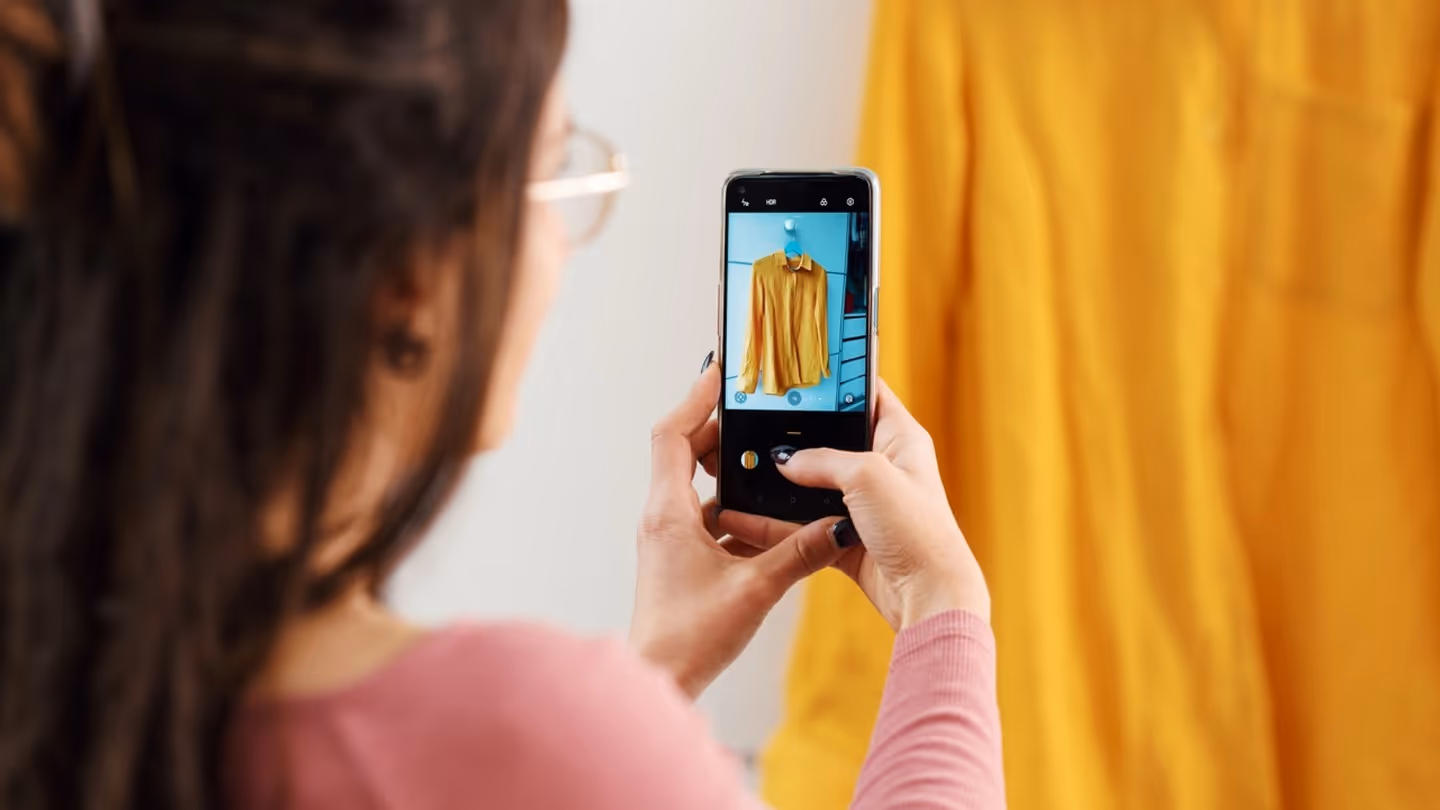 Person photographing a blouse with a smartphone for resale