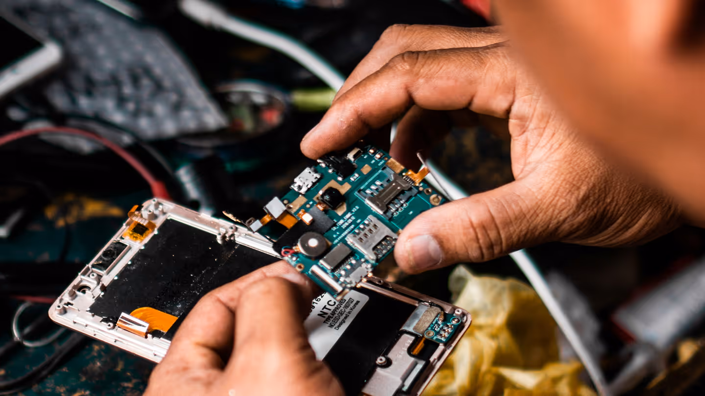A person is carefully repairing the internal components of an opened smartphone.