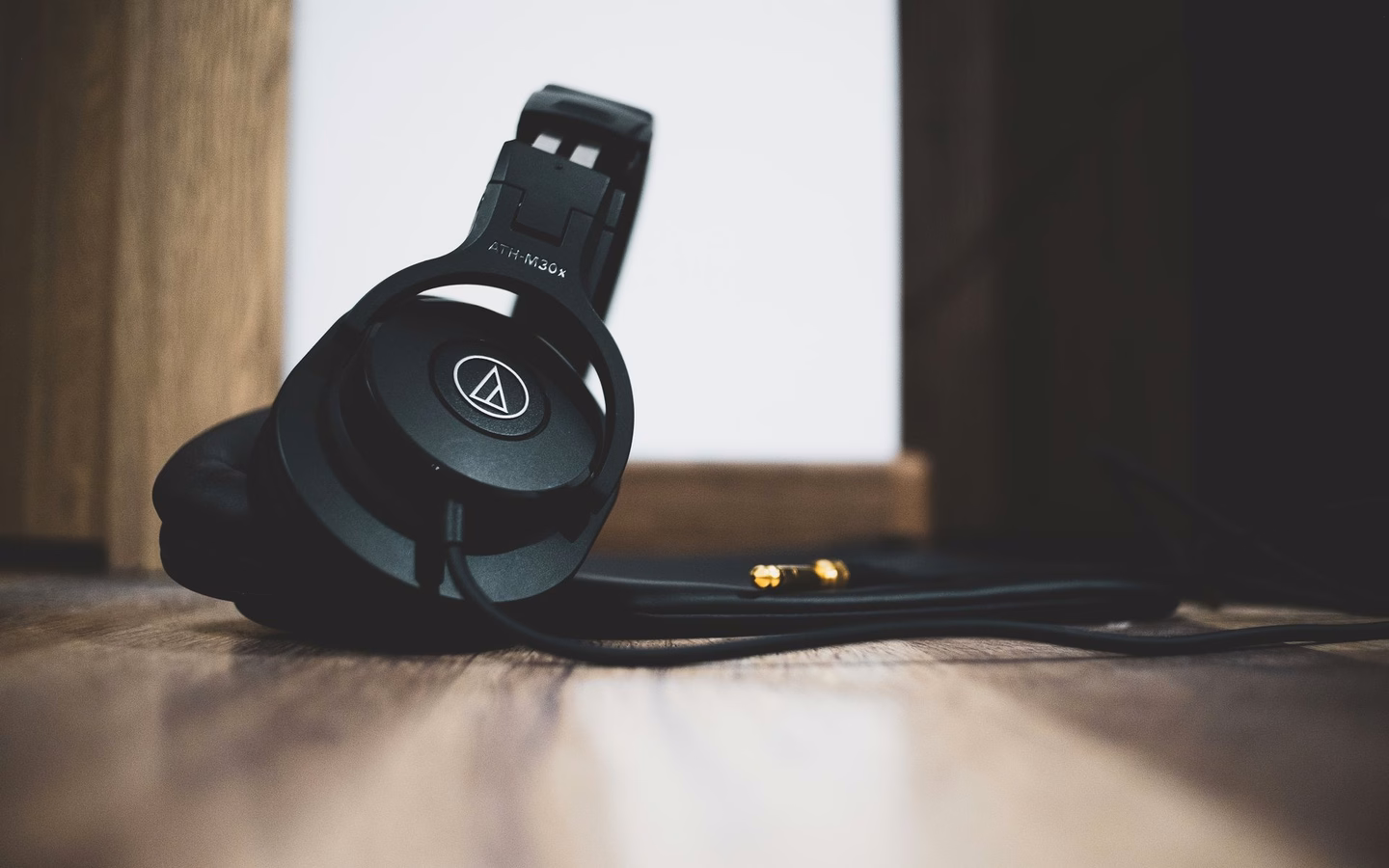 Black over-ear headphones with cable resting on wood, used hifi gear that holds its value