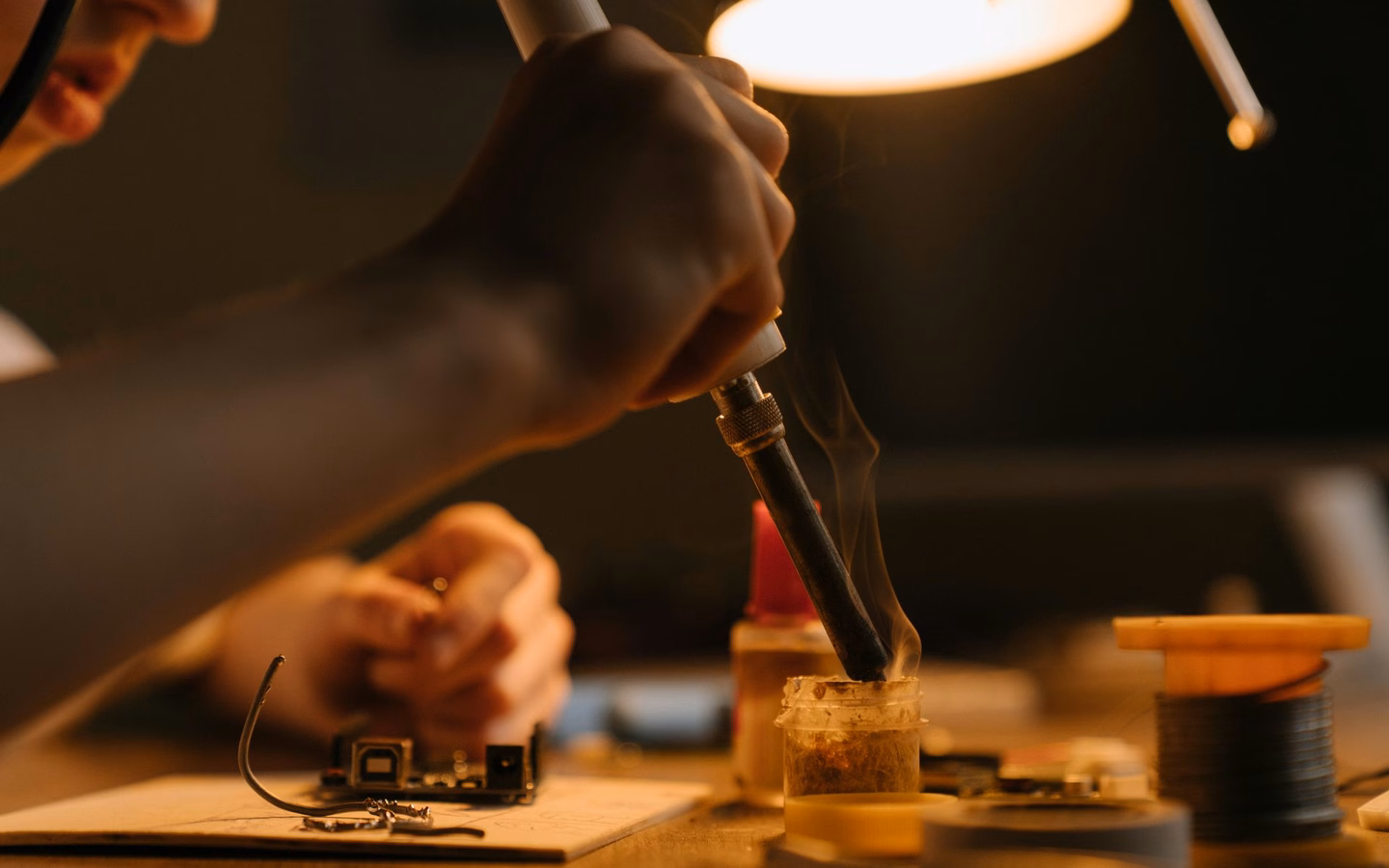 Technician soldering audio electronics in a workshop, headphone refurbishment up close