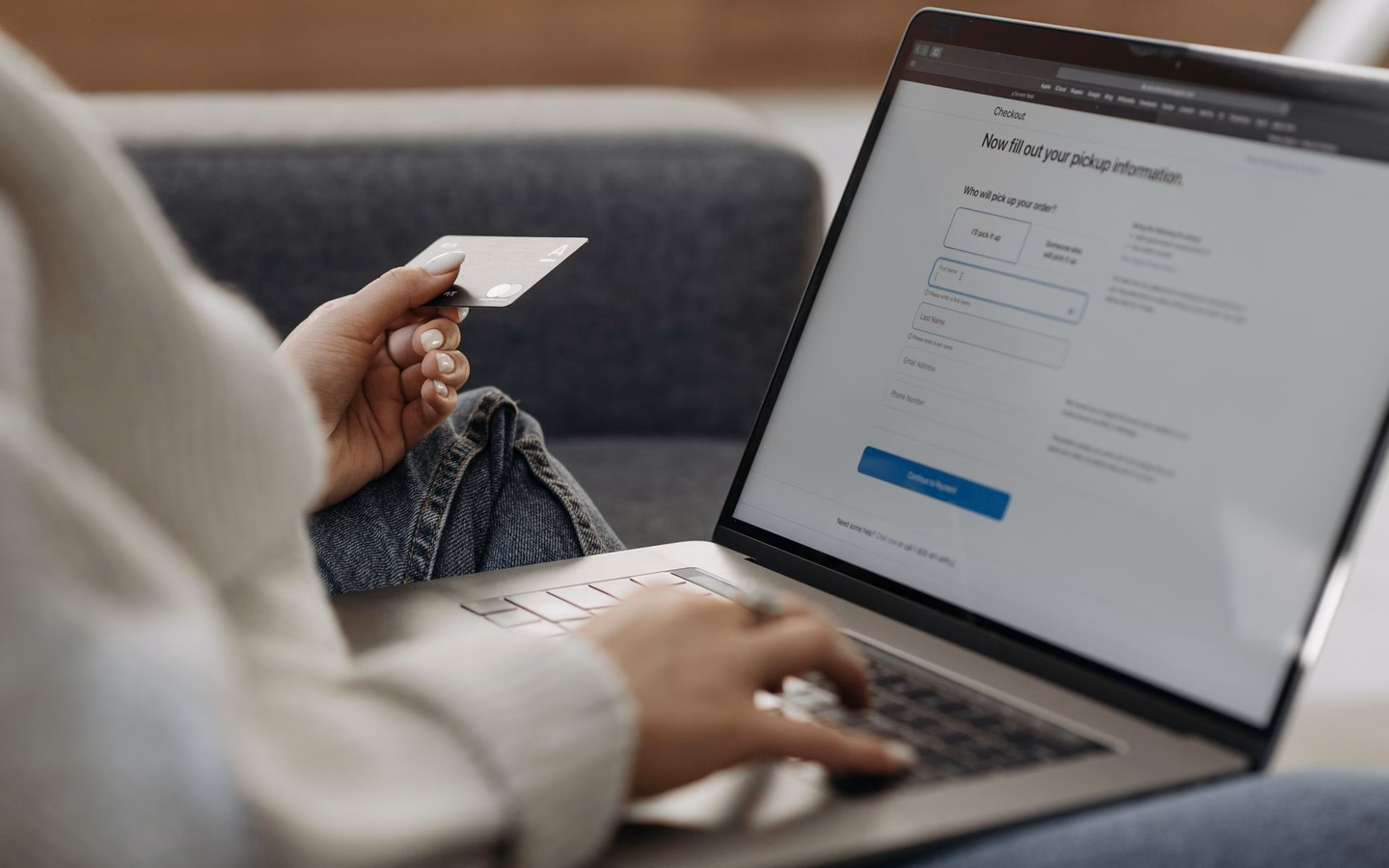 Kundin füllt zu Hause am Laptop ein Online-Formular für die Trade-In-Bewertung aus, Bankkarte in der Hand
