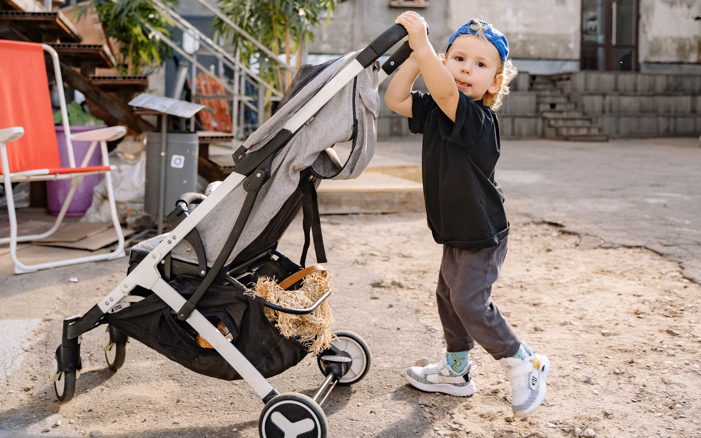 Toddler pushing a secondhand stroller, example of used baby gear