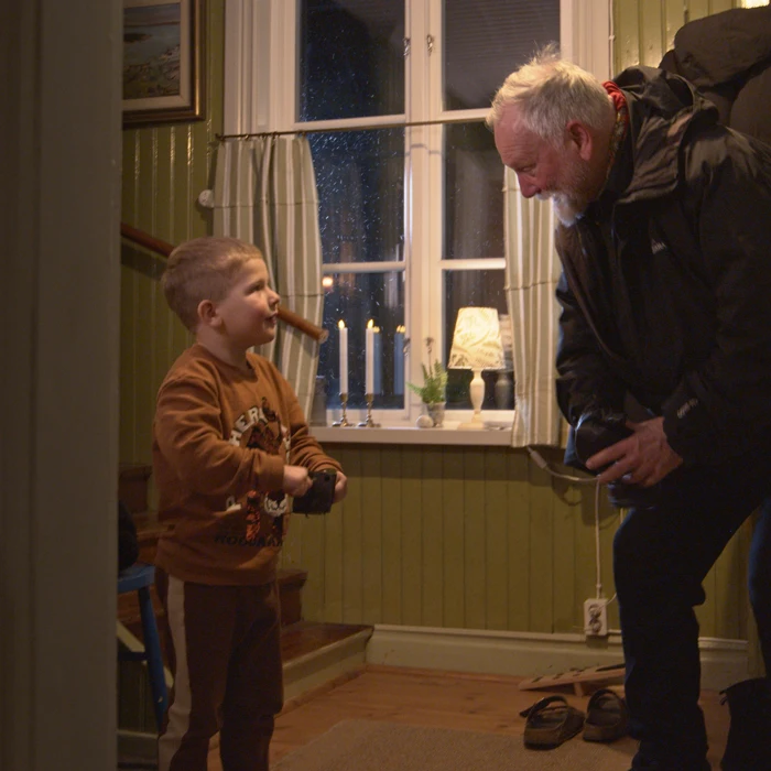 En pojke och en man hälsar på varandra i en hall