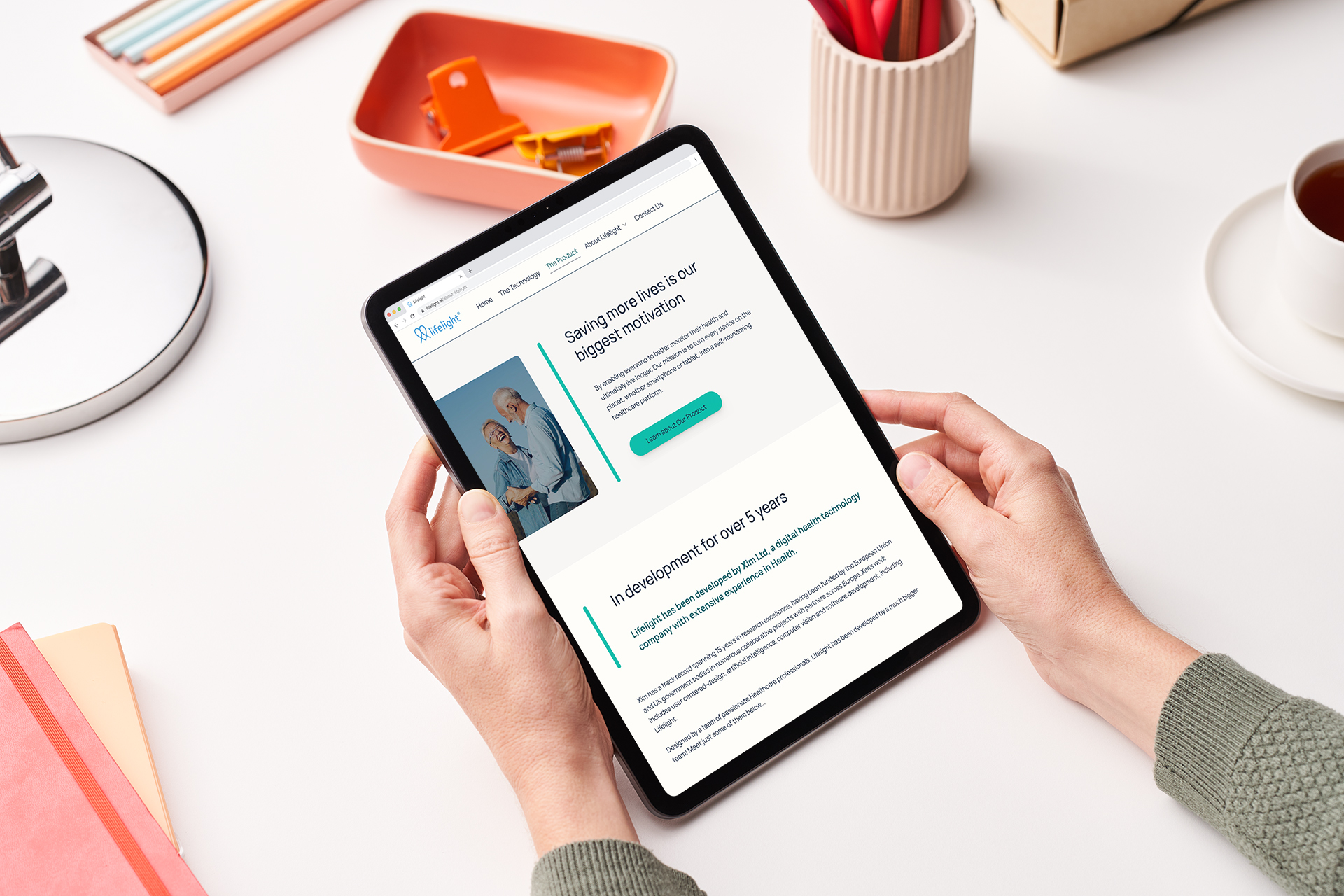 Man's hands holding an ipad with the website on it