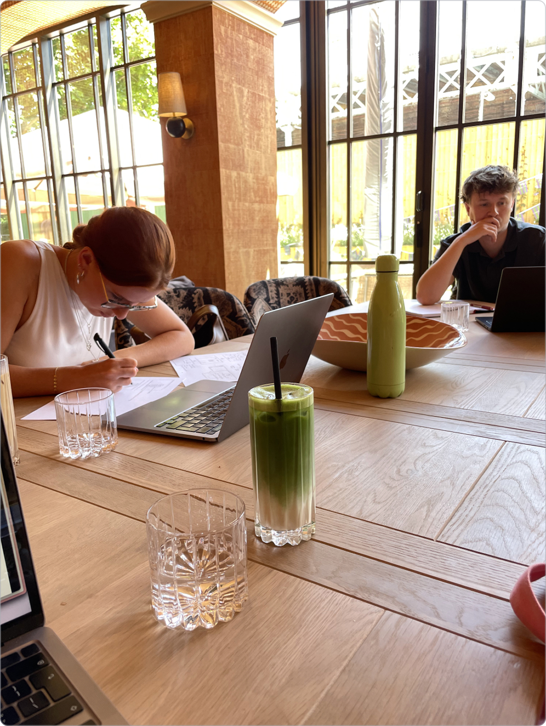 Two designers at a table working with laptops and sketchpads