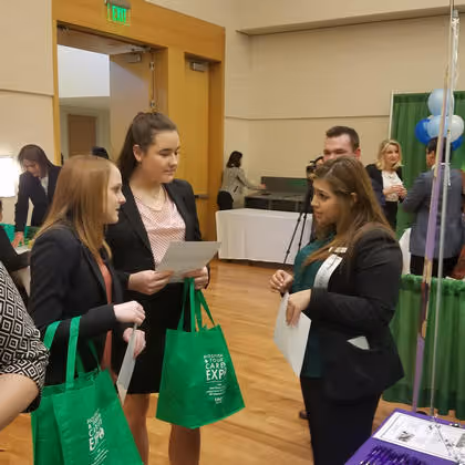 Staff member talking to two students during a job expo