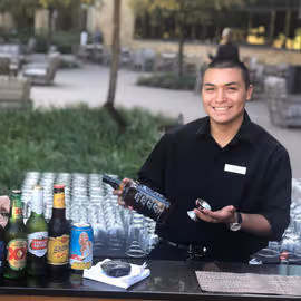 A bartender smiling and offering drinks