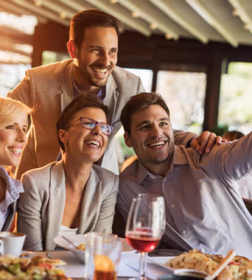 Friends smiling and hugging at lunch. 