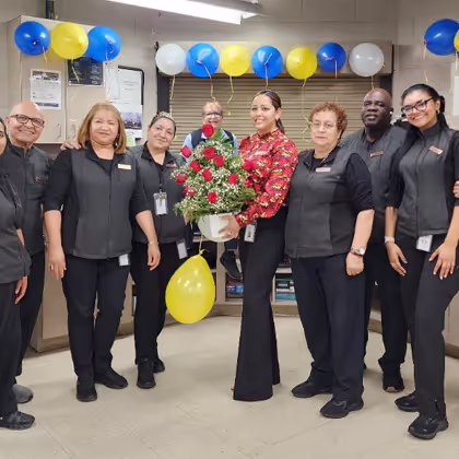 Group of employees celebrating with flowers and balloons.