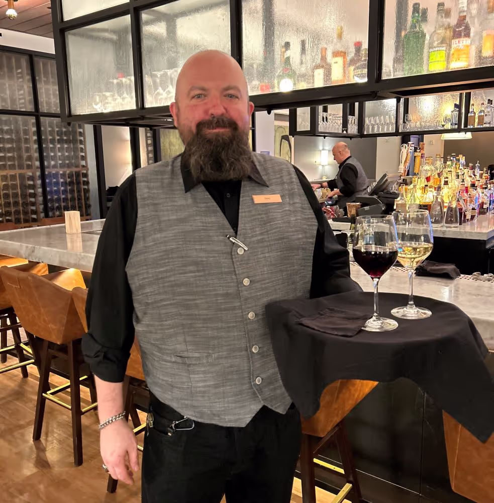 Waiter holding a tray with two glasses of wine.