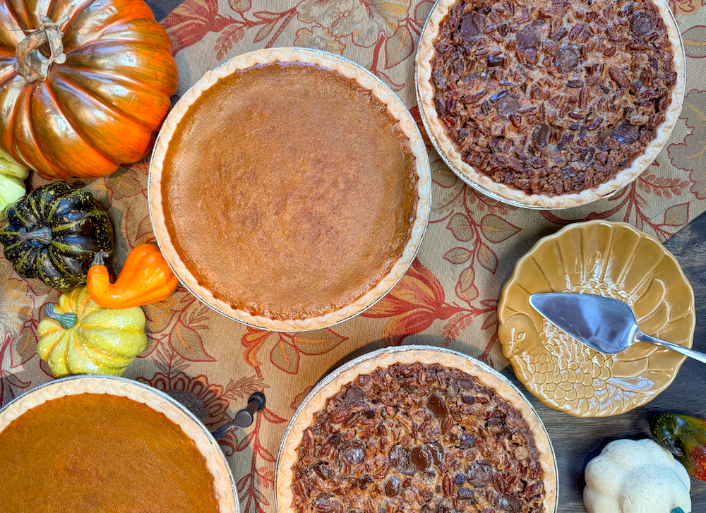 A display case full of pastries with someone reaching for a bun