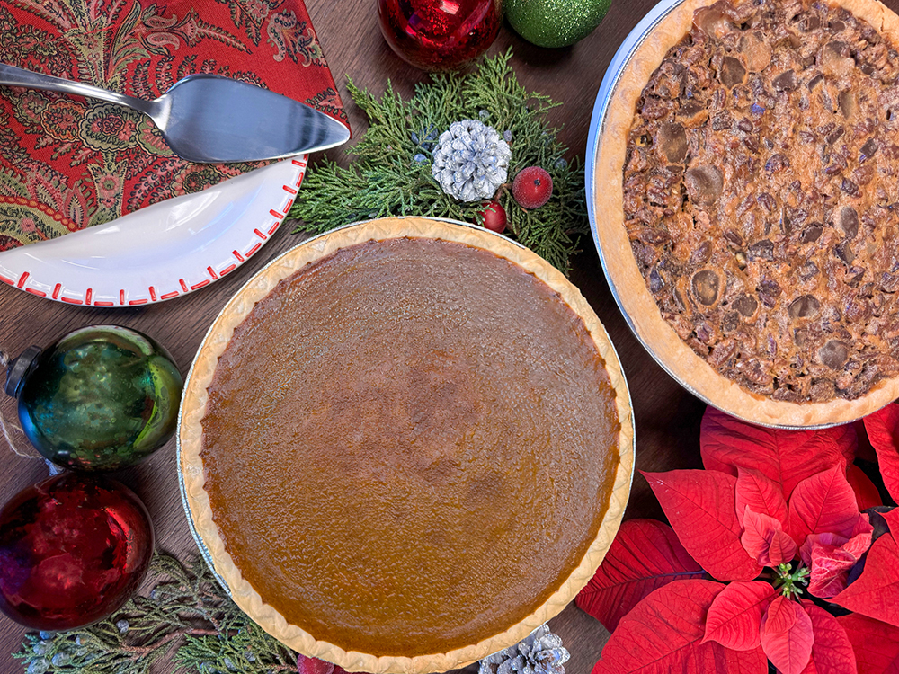 A display case full of pastries with someone reaching for a bun