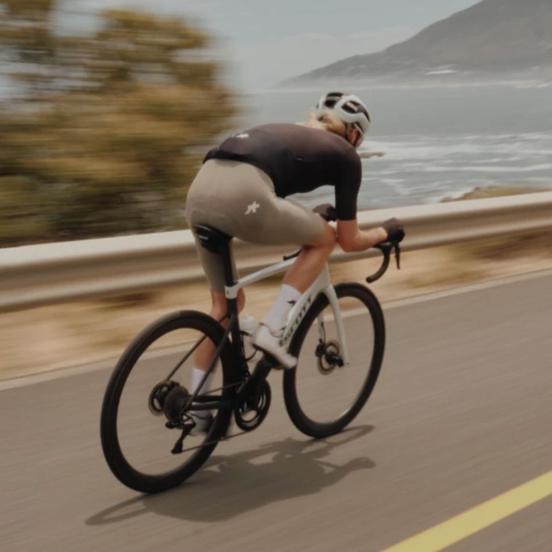 Cyclist riding on a coastal road wearing premium cycling kit