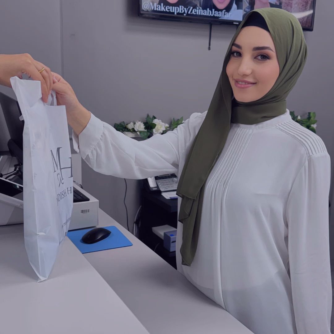Happy customer receiving a Modish Hijab shopping bag at checkout counter.