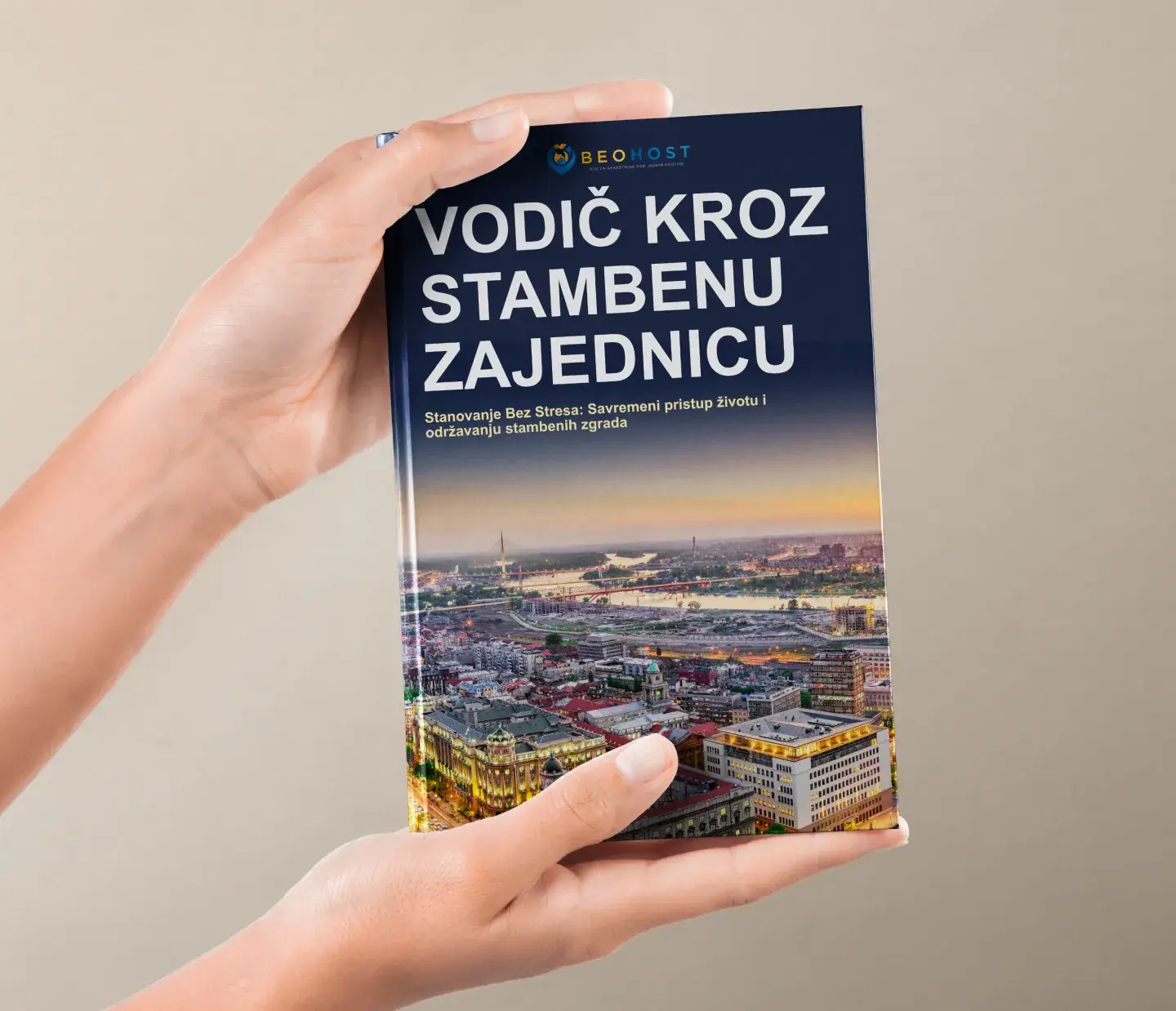 Osoba koja drži knjigu Vodič kroz stambenu zajednicu sa slikom grada na koricama.